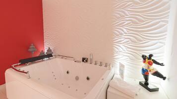 A modern bathroom with a large bathtub, a red accent wall, and a decorative wall panel.