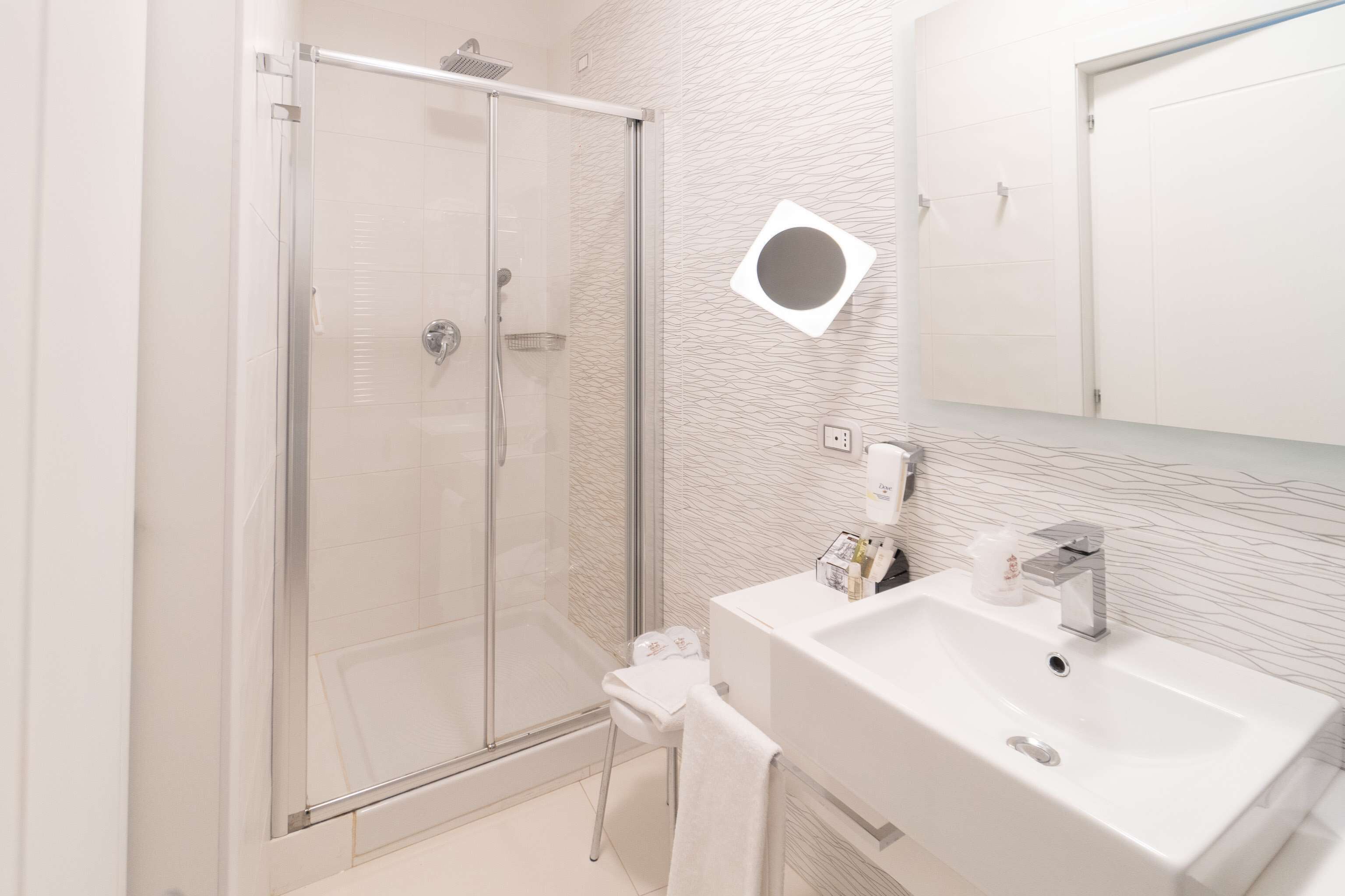 Ein modernes Badezimmer mit einer Duschkabine aus Glas, einem weißen Waschbecken und einem Handtuchhalter.