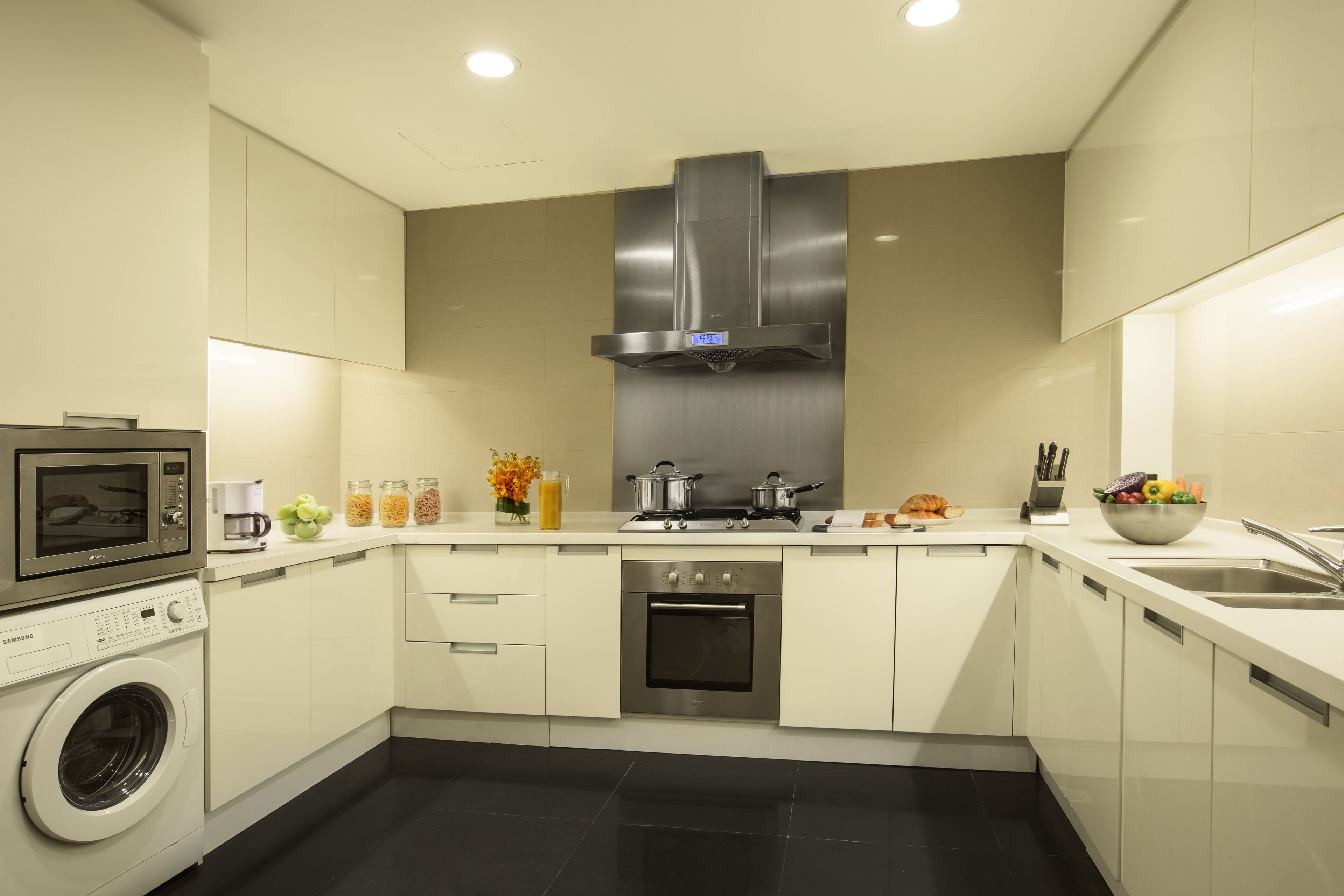A modern kitchen with a built-in microwave, oven, and stainless steel range hood.