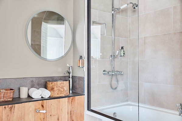 Une salle de bain moderne avec une douche à parois de verre, un miroir rond et un meuble-lavabo en bois.