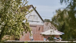 A rustic brick building with a sloped roof, surrounded by lush greenery and a clear sky. - The Bucks Head (Southampton)
