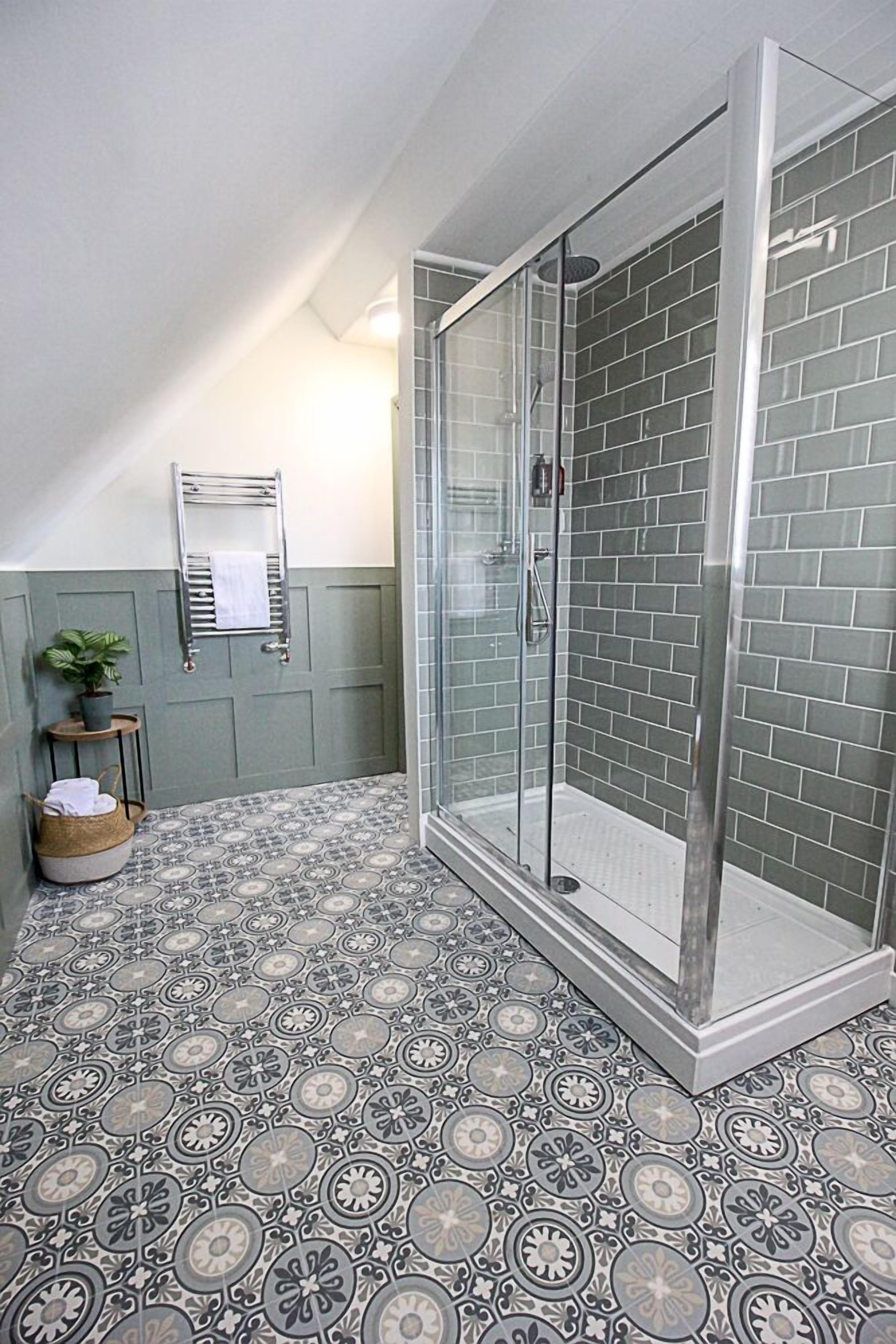 A shower with glass doors, a patterned floor, and a towel rack with a towel.