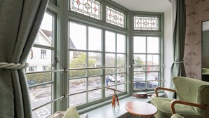A room with large bay windows, a telescope, a round table, and green armchairs. - The Bugle Coaching Inn (Yarmouth)