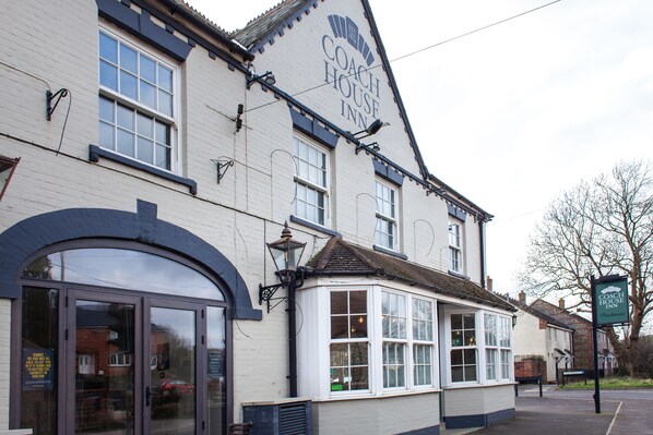 A Coach House Inn with a traditional white facade, large windows, and a prominent sign.