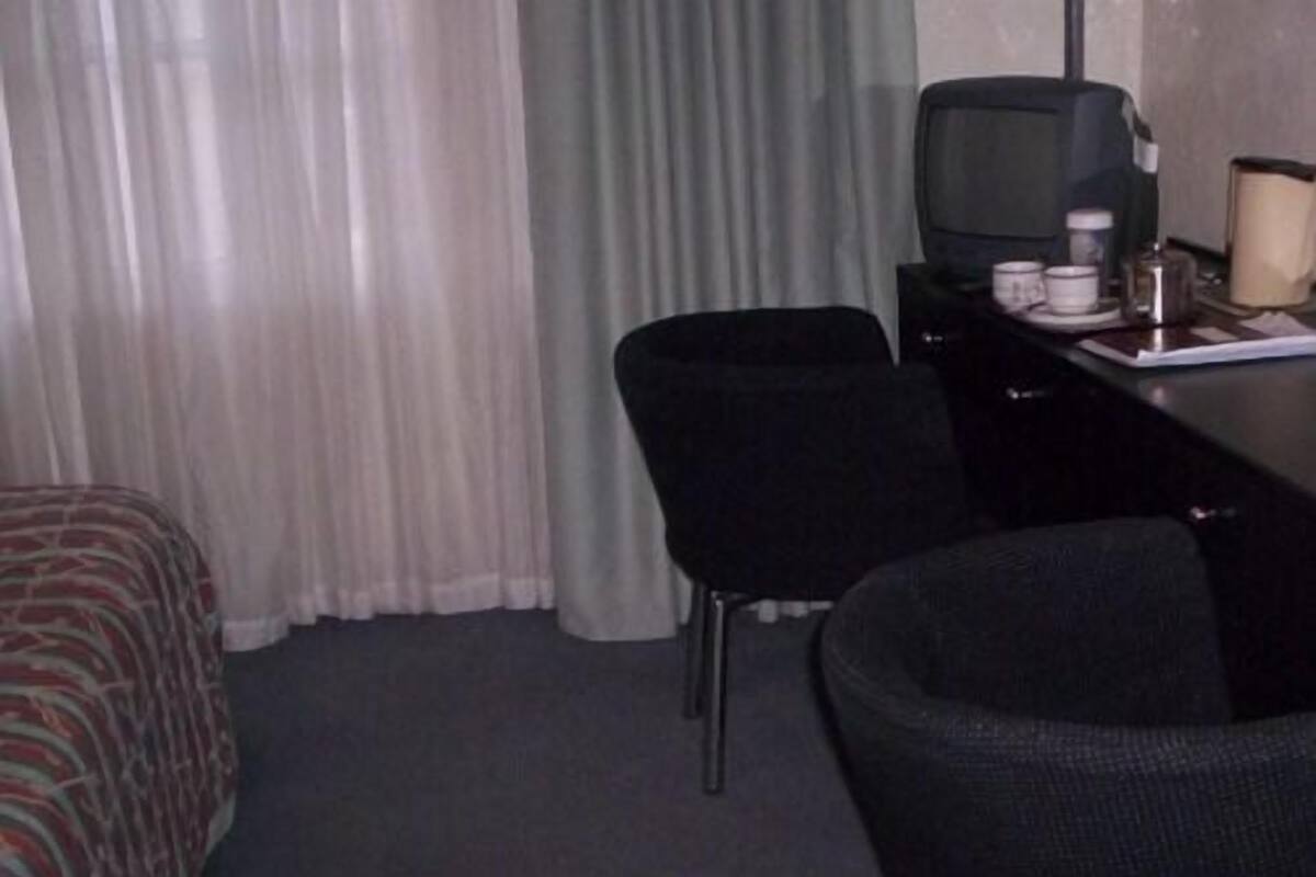 A hotel room with a bed, a desk with a television, a chair, and a coffee maker.