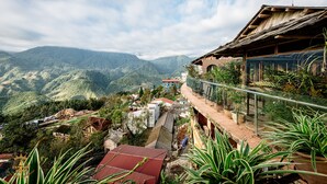 Un paysage montagneux avec un bâtiment doté d’un balcon donnant sur la vallée.