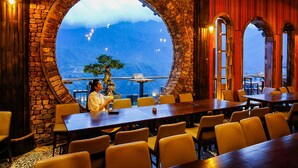 Un restaurant doté d’une grande fenêtre en arc d’où l’on peut admirer un paysage montagneux.