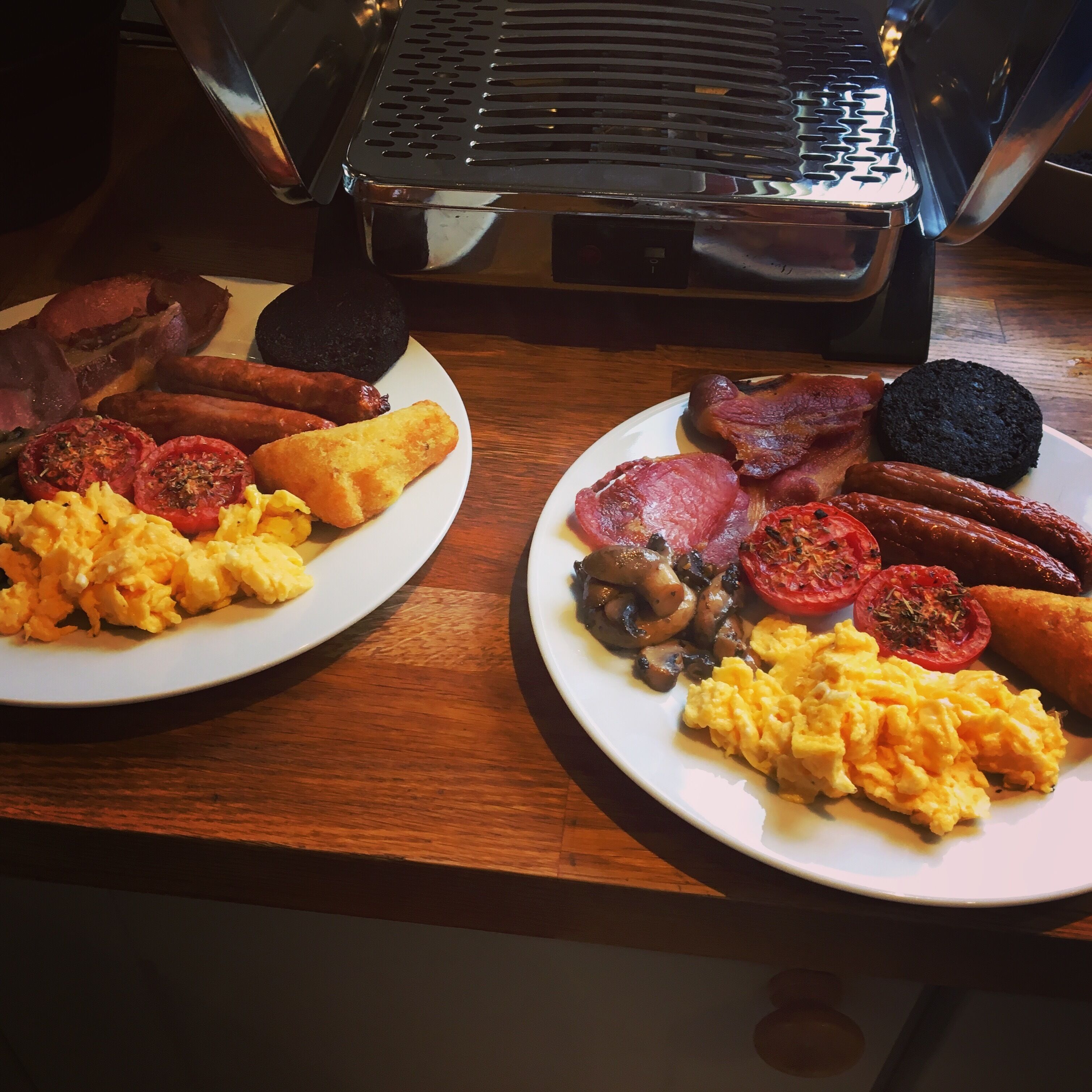Two plates of breakfast food on a wooden table.