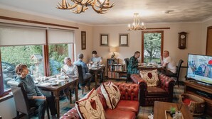 Una sala de estar acogedora con chimenea, sofás de cuero, una mesa de comedor y un televisor.
