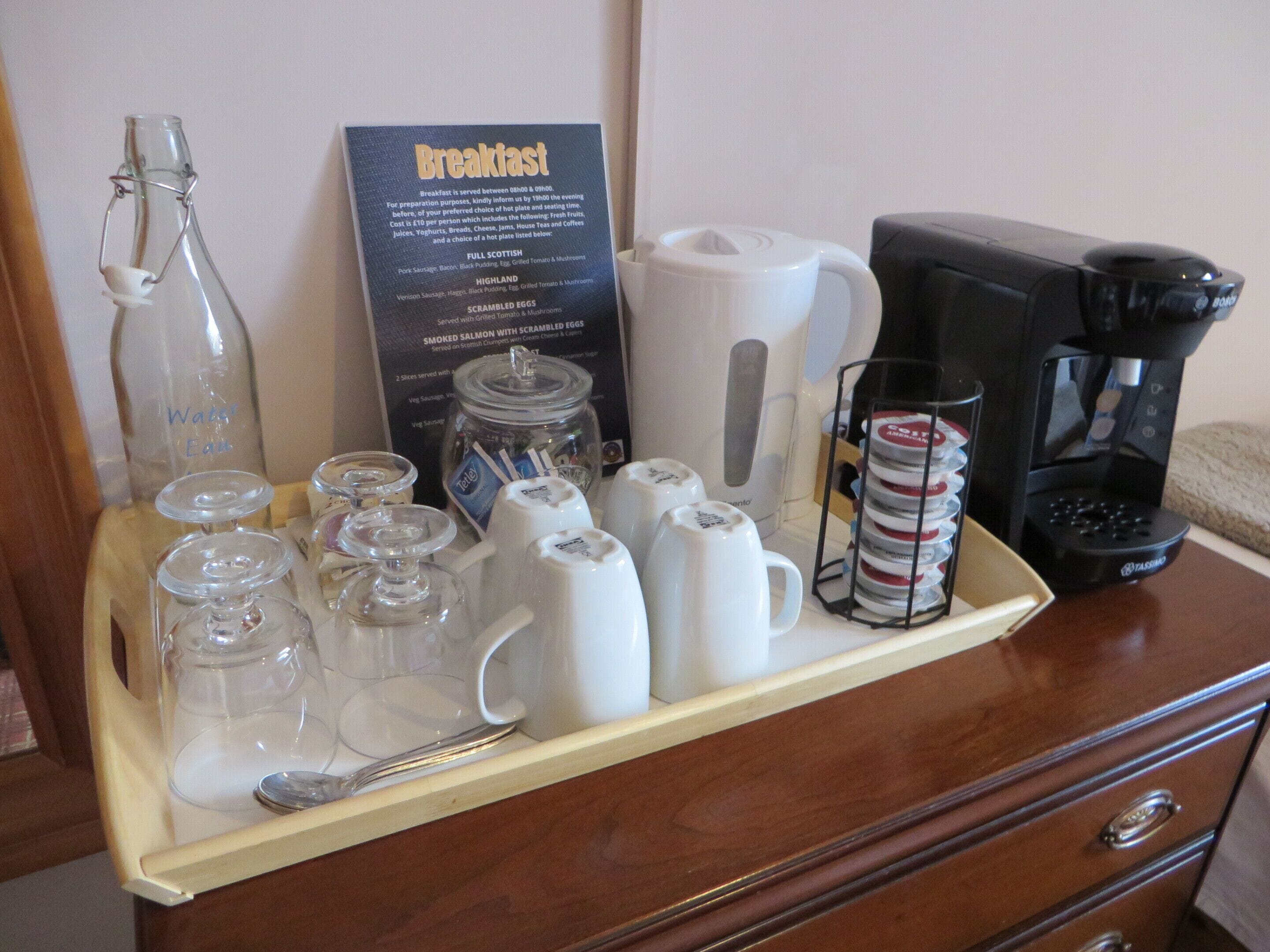A breakfast tray with various items including a coffee maker, cups, and a menu.