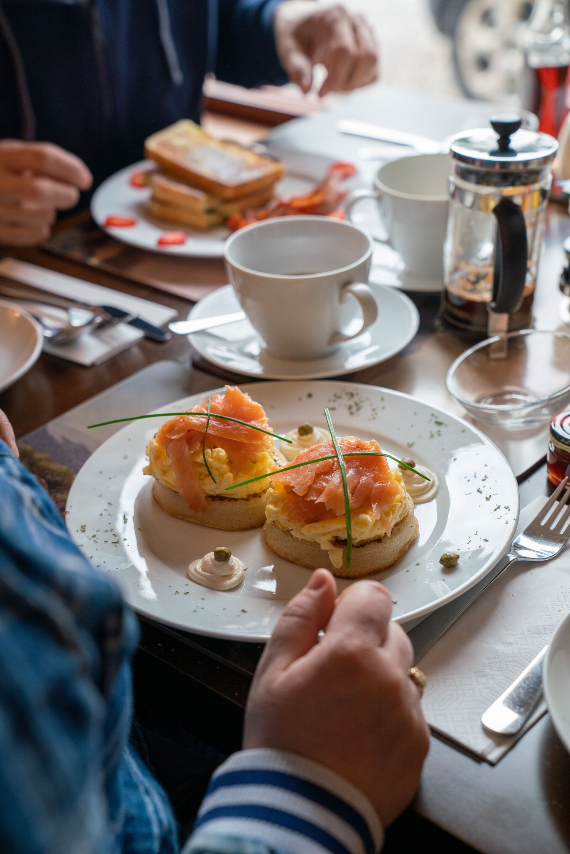 Ein Esstisch mit Tellern voller Speisen, einer Kaffeekanne und Besteck.