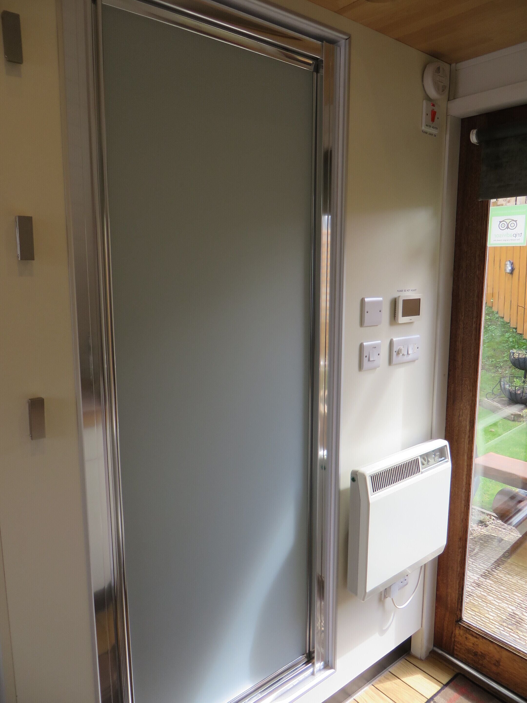 A room with a sliding door, a thermostat, and a window with a view of a garden.