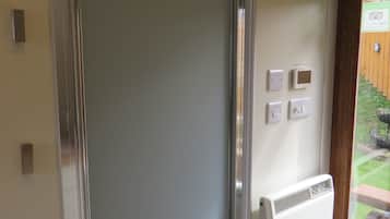 A room with a sliding door, a thermostat, and a window with a view of a garden.