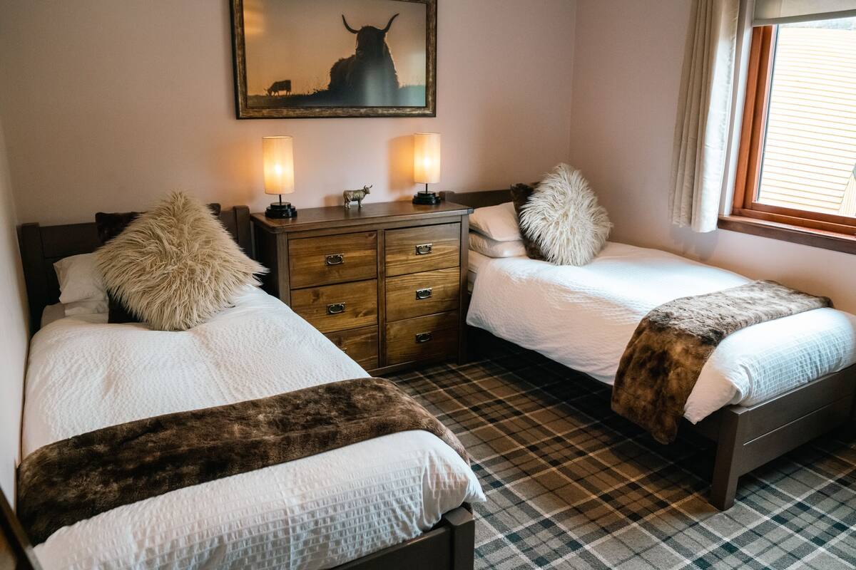 Ein Hotelzimmer mit zwei Betten, einer Holzkommode und einem Gemälde von einem Stier.