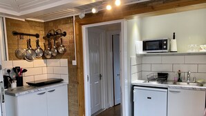 A compact kitchen with white cabinetry, a wooden floor, and a brick accent wall. - Fourwinds Leisure (March)