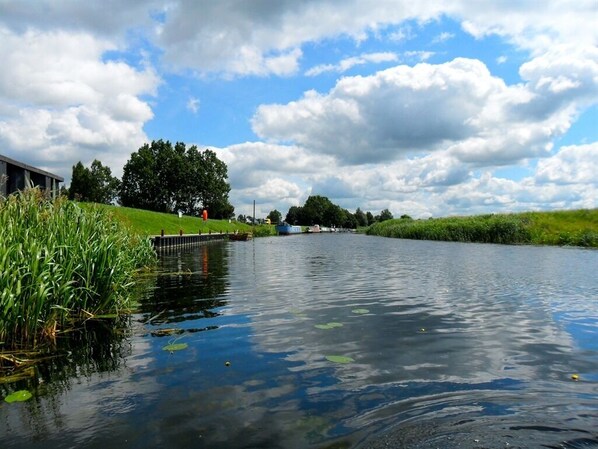 A calm river with a wooden dock and a building on the left.