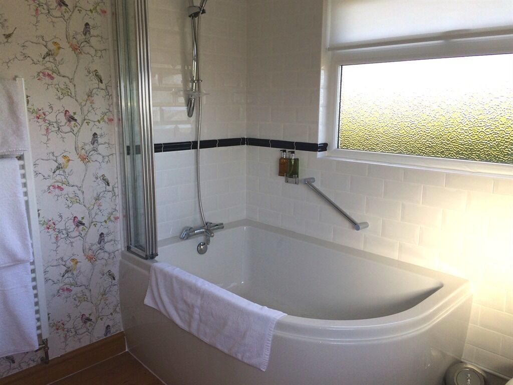 Une salle de bain avec une baignoire, une douche et une fenêtre.