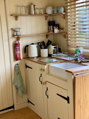A kitchen with wooden cabinets, a sink, a coffee maker, a toaster, and a window with blinds.