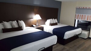 A hotel room with two beds, a bedside table with a lamp, a TV, and a window with blinds. - Baymont by Wyndham Ridgeland I-95 (Ridgeland)