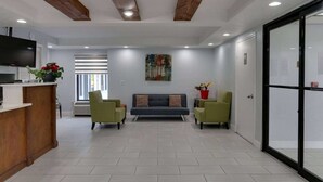 A modern interior with a reception desk, a sofa, two armchairs, and a large window with blinds. - Baymont by Wyndham Ridgeland I-95 (Ridgeland)