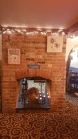 Una chimenea de ladrillo con un letrero encima, un plato decorativo debajo y una guirnalda de luces sobre la chimenea.