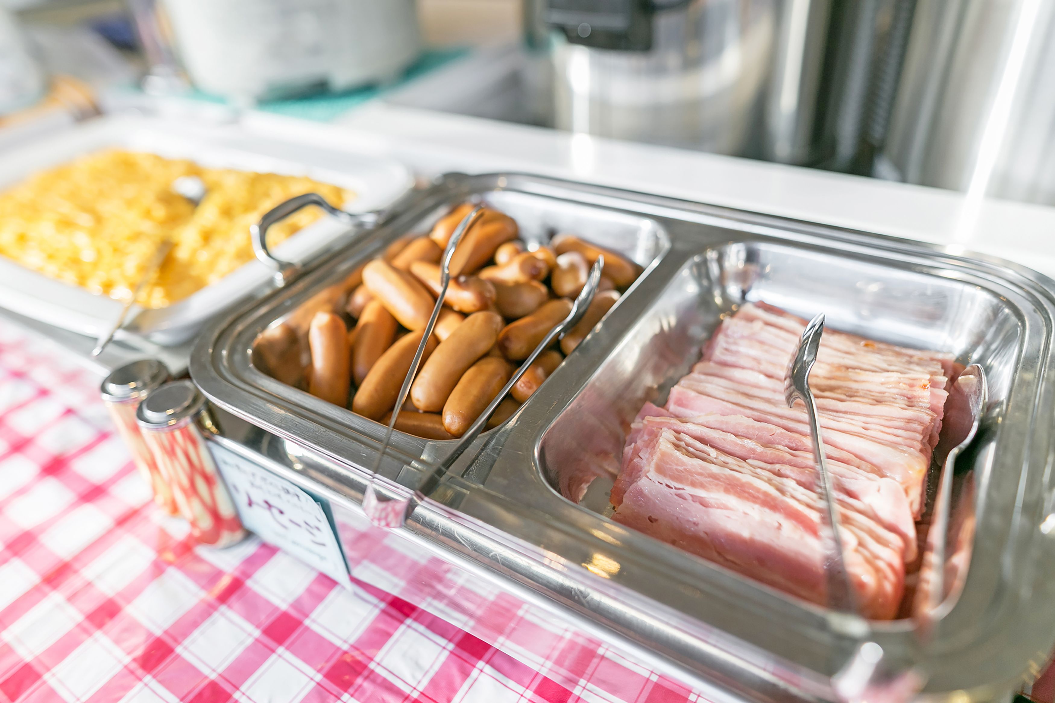 A buffet with various food items including sausages and sliced ham.