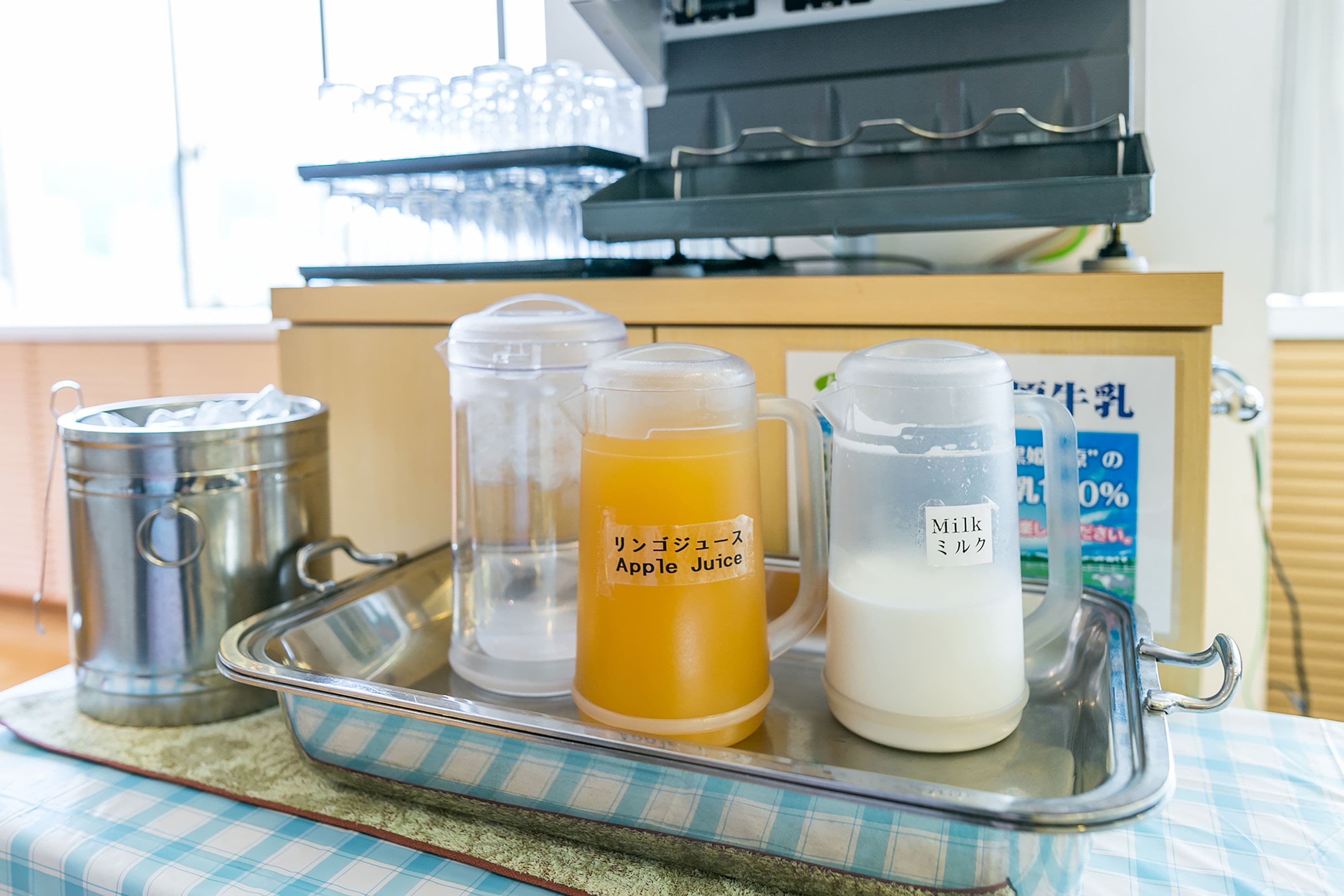 A tray with a milk jug, a pitcher of apple juice, and a container of milk.