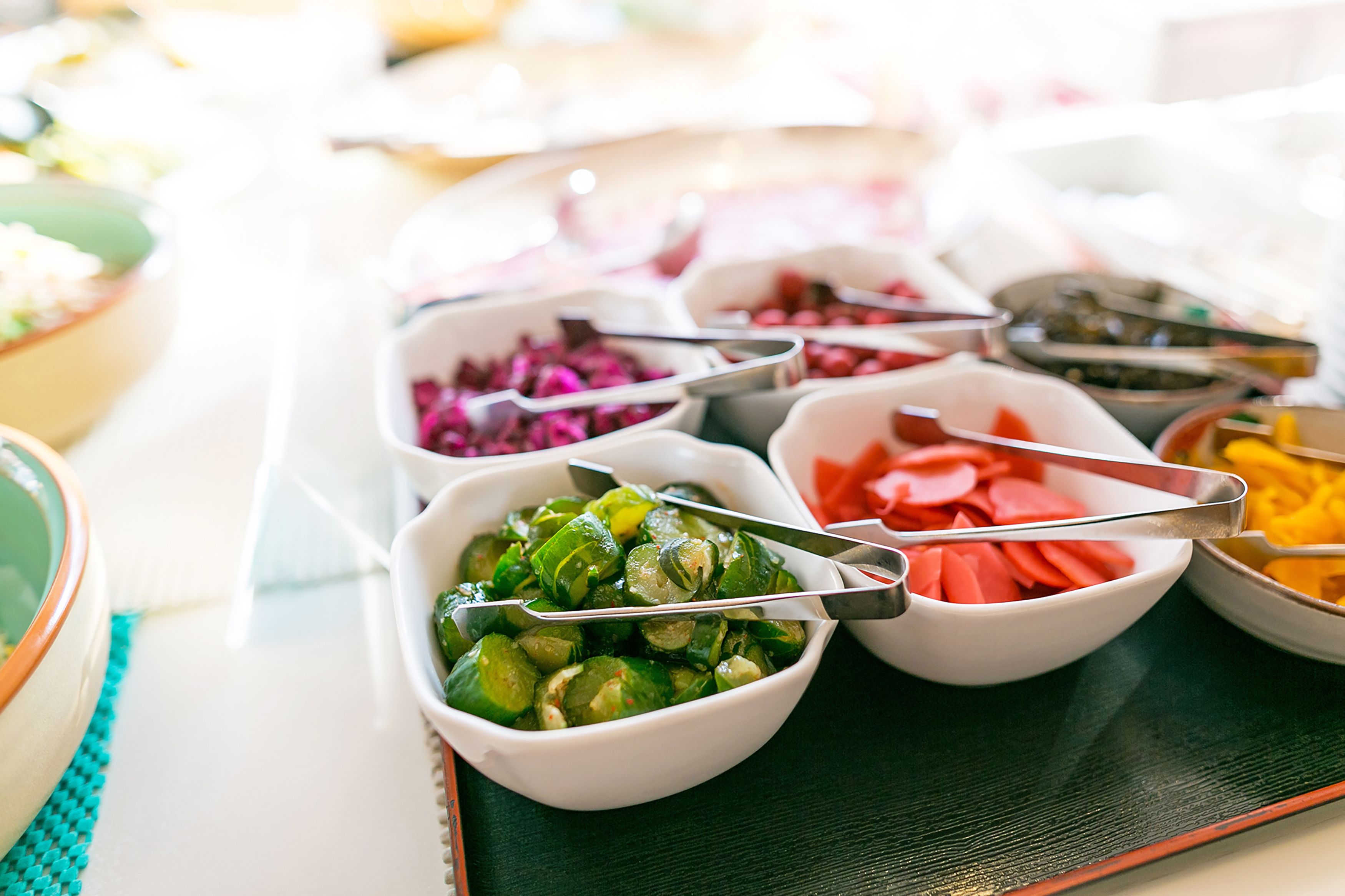 A buffet table with various food items in bowls, including vegetables and fruits.