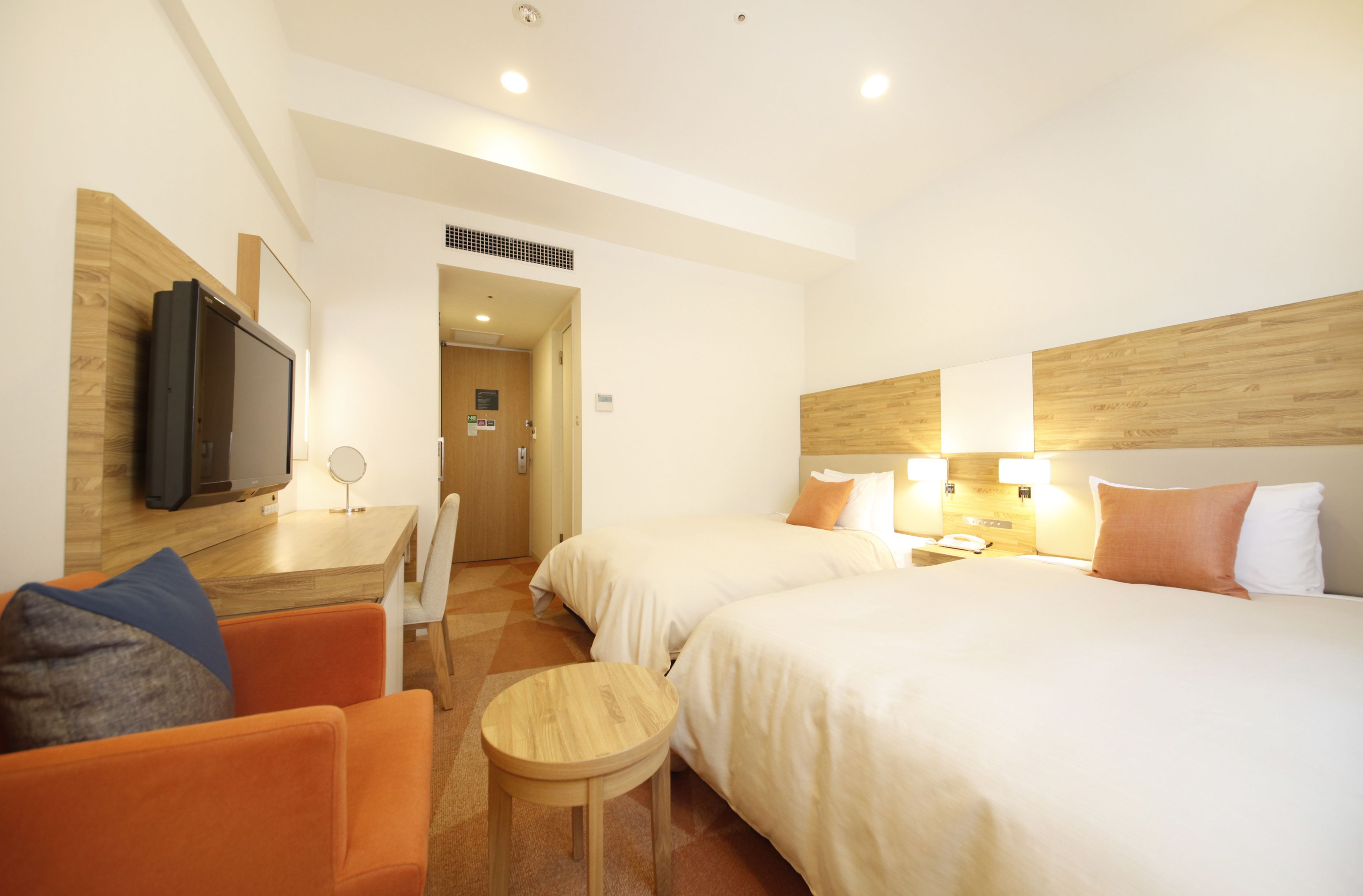 Habitación de hotel con dos camas, televisión, escritorio con silla y una mesita.