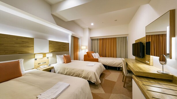 A hotel room with two beds, a desk, a mirror, a television, and a lamp.