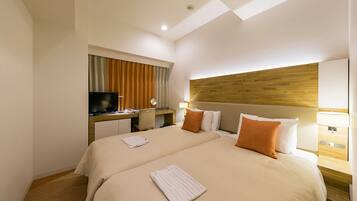 A hotel room with two beds, a desk with a TV, and a wooden headboard.