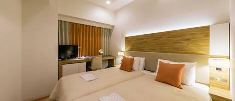 Habitación de hotel con dos camas, un escritorio con televisor y un cabecero de madera.