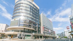 A modern hotel with a curved facade, multiple floors, and a prominent entrance with a staircase.