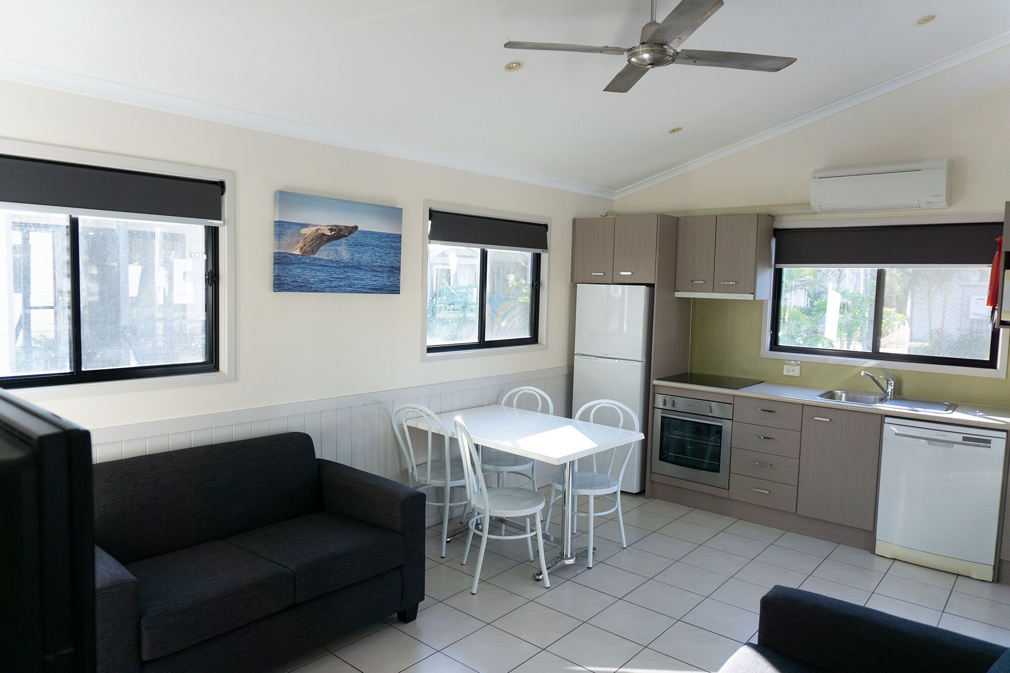 A compact kitchen with a dining area, a ceiling fan, and a refrigerator.