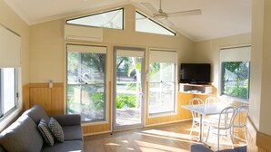 Amplia sala de estar con sofá, una mesa de comedor con sillas, ventilador de techo y televisor.