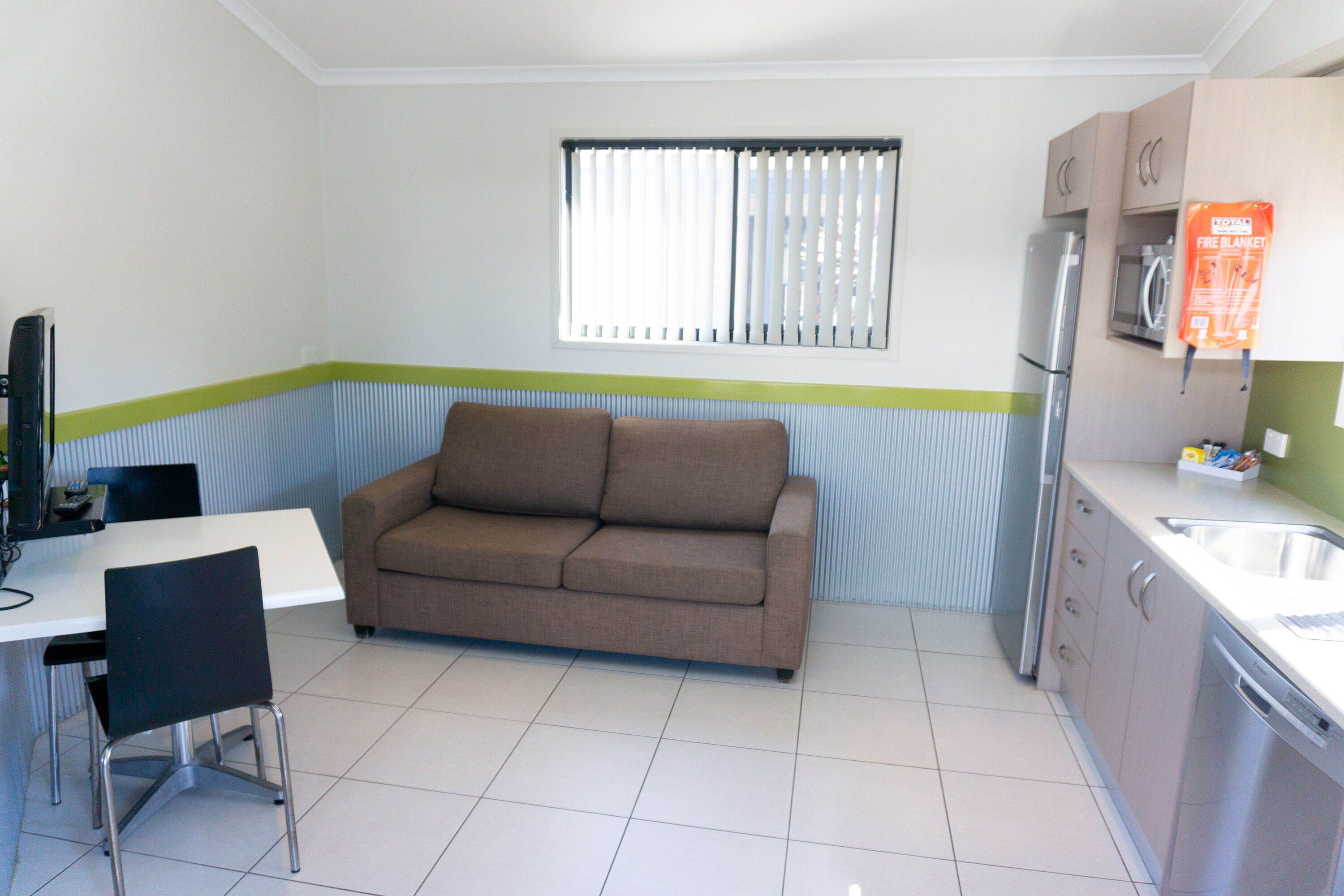 Cocina compacta con sofá, mesa, sillas y refrigerador.