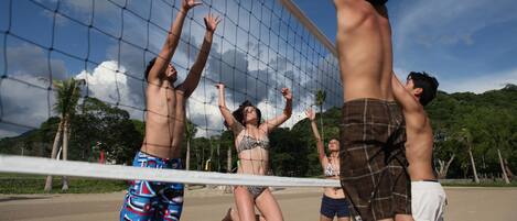 A beach volleyball game with players in swimwear.