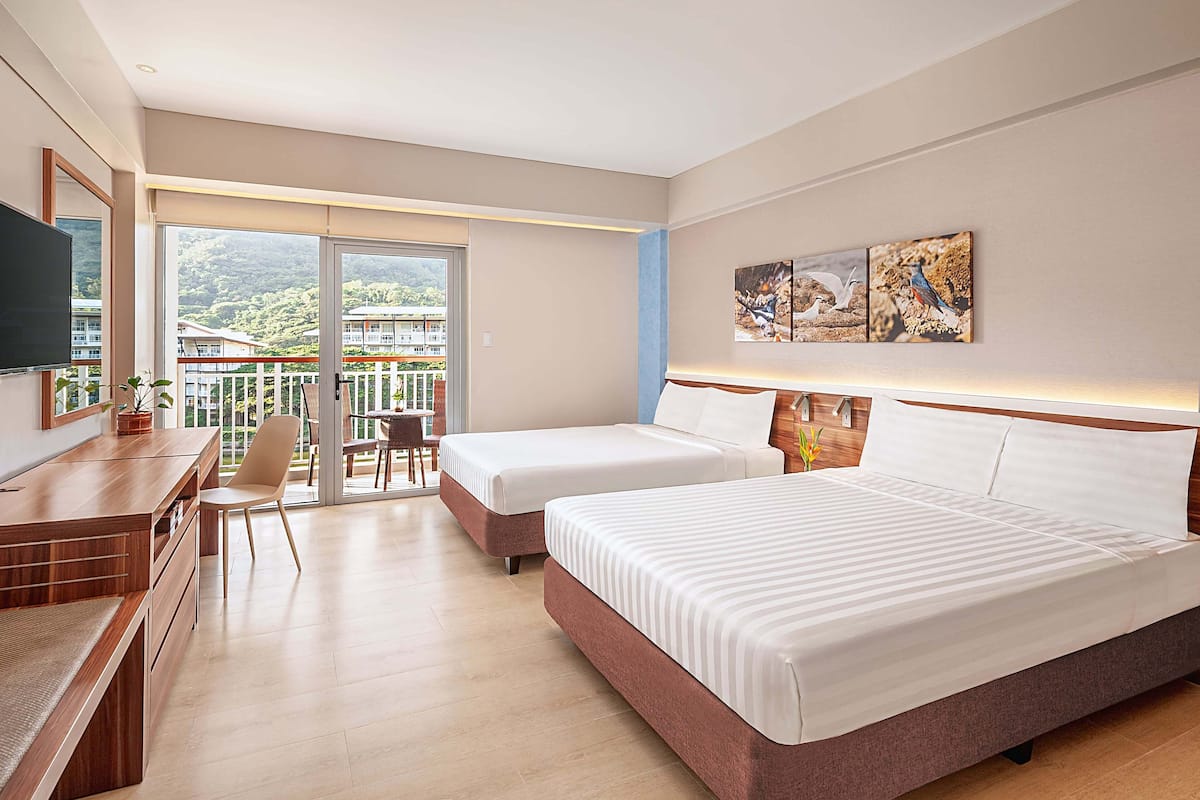 Ein Hotelzimmer mit zwei Betten, einem Schreibtisch und einem Balkon mit Bergblick.