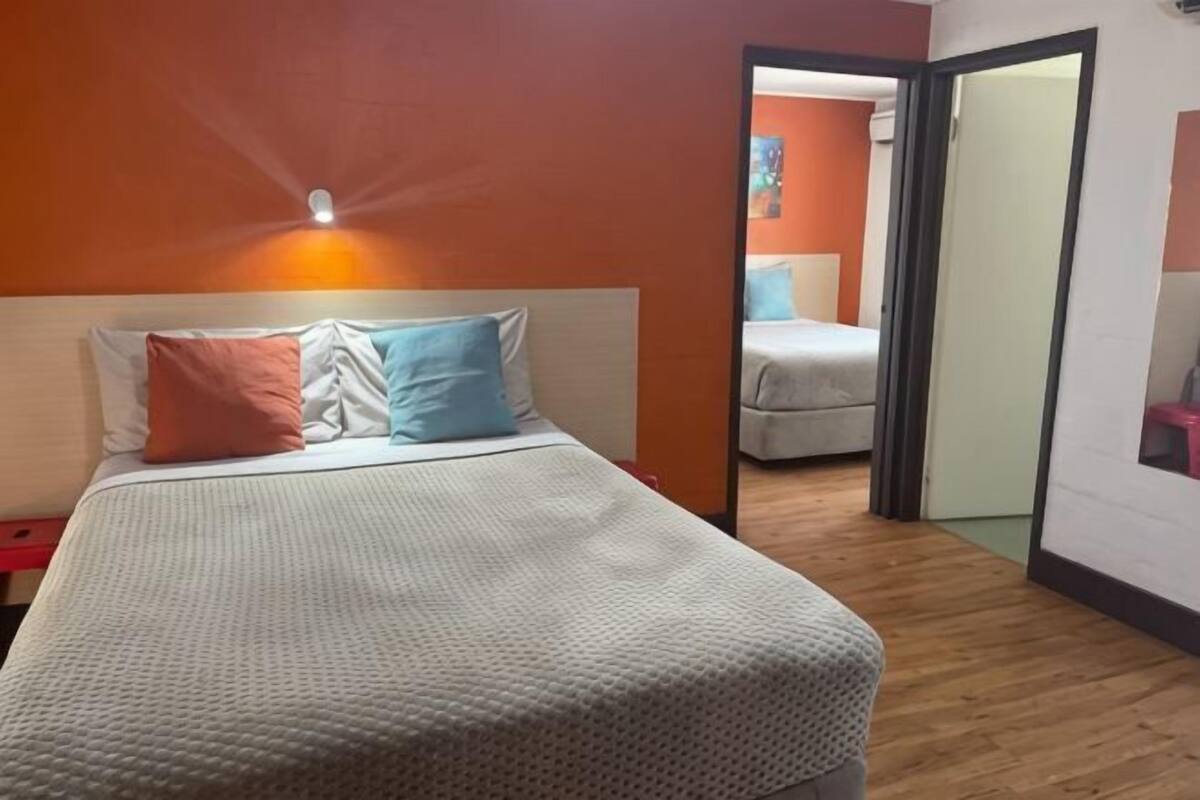 A bedroom with a bed, two pillows, a nightstand, and a mirror.