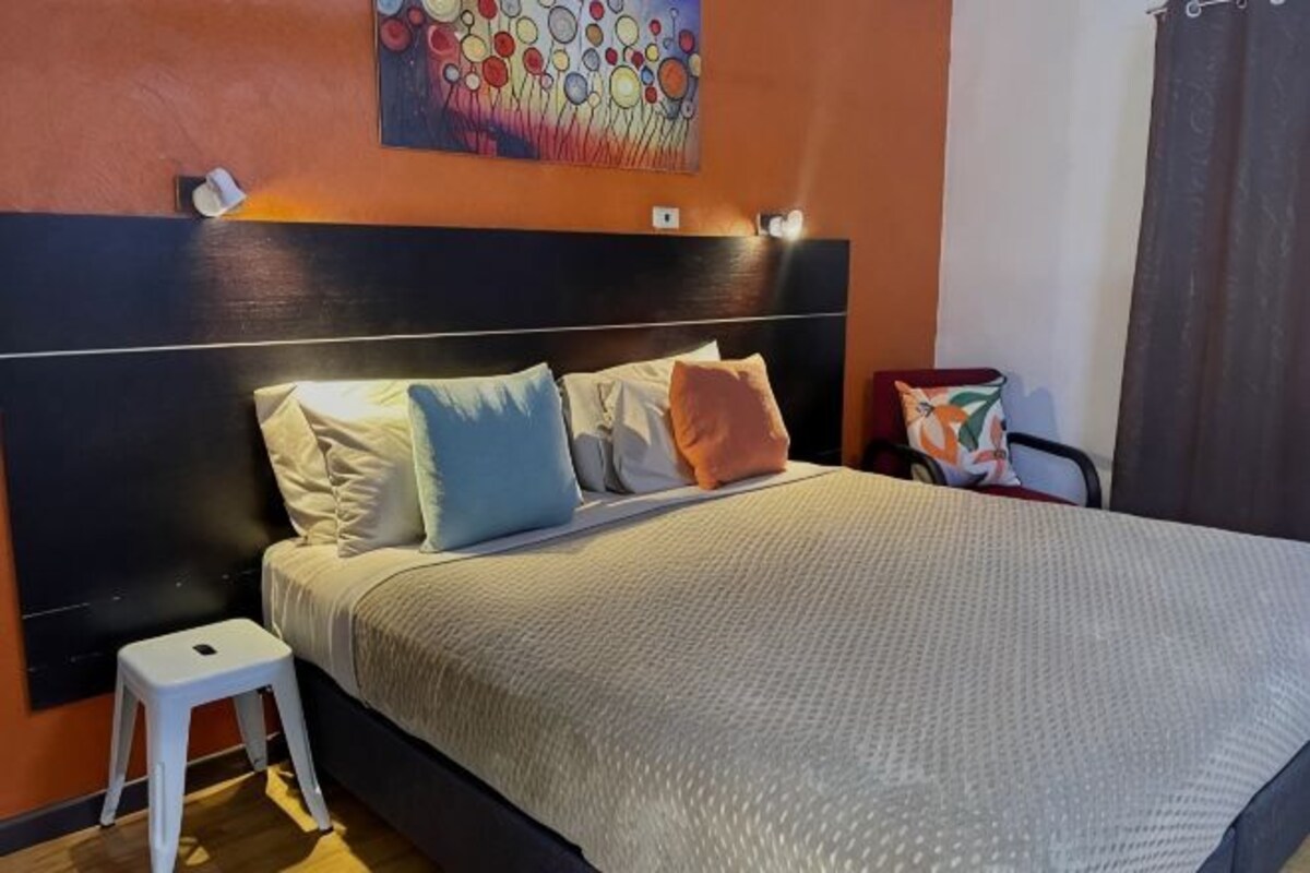 A bed with a headboard, pillows, a bedside table, and a wall-mounted light fixture.