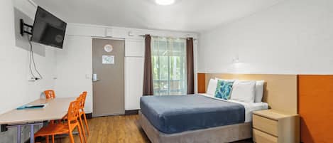 Une chambre à coucher comprenant un lit, une table de chevet et un bureau avec des chaises.