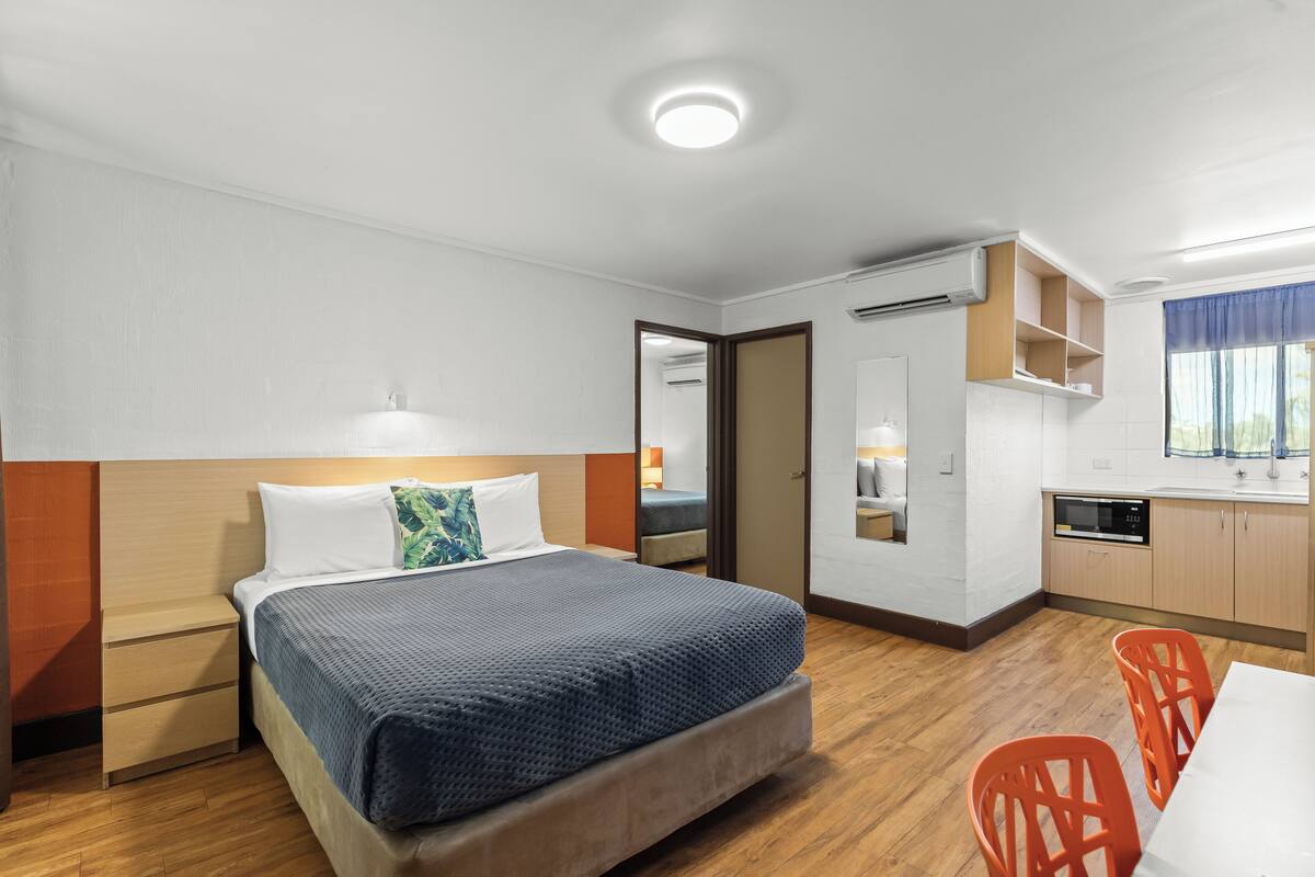 A compact hotel room with a bed, a desk, and a kitchenette.