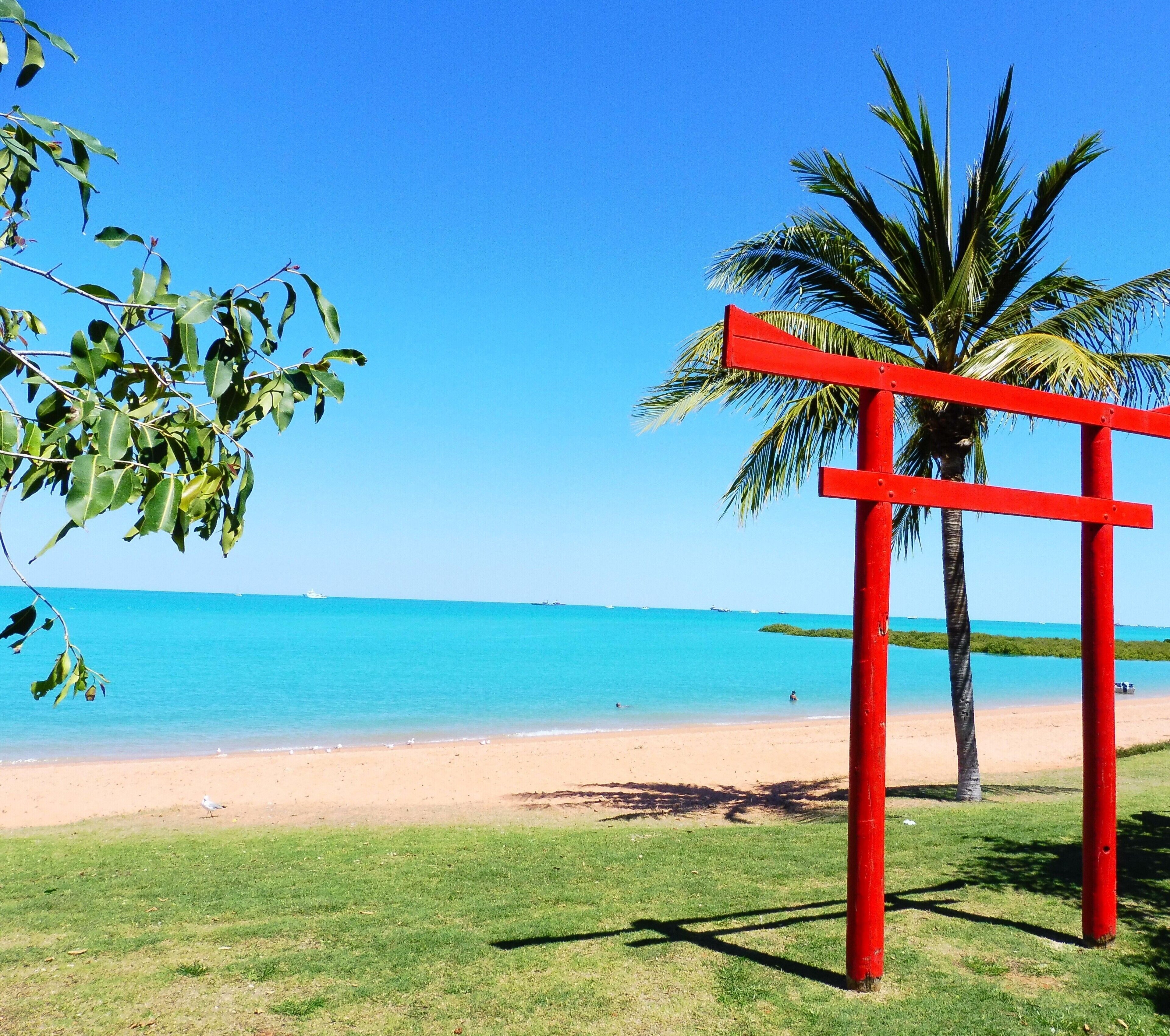 A beach with a red structure, clear blue sky, and calm sea.