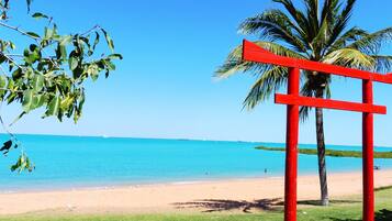 A beach with a red structure, clear blue sky, and calm sea.