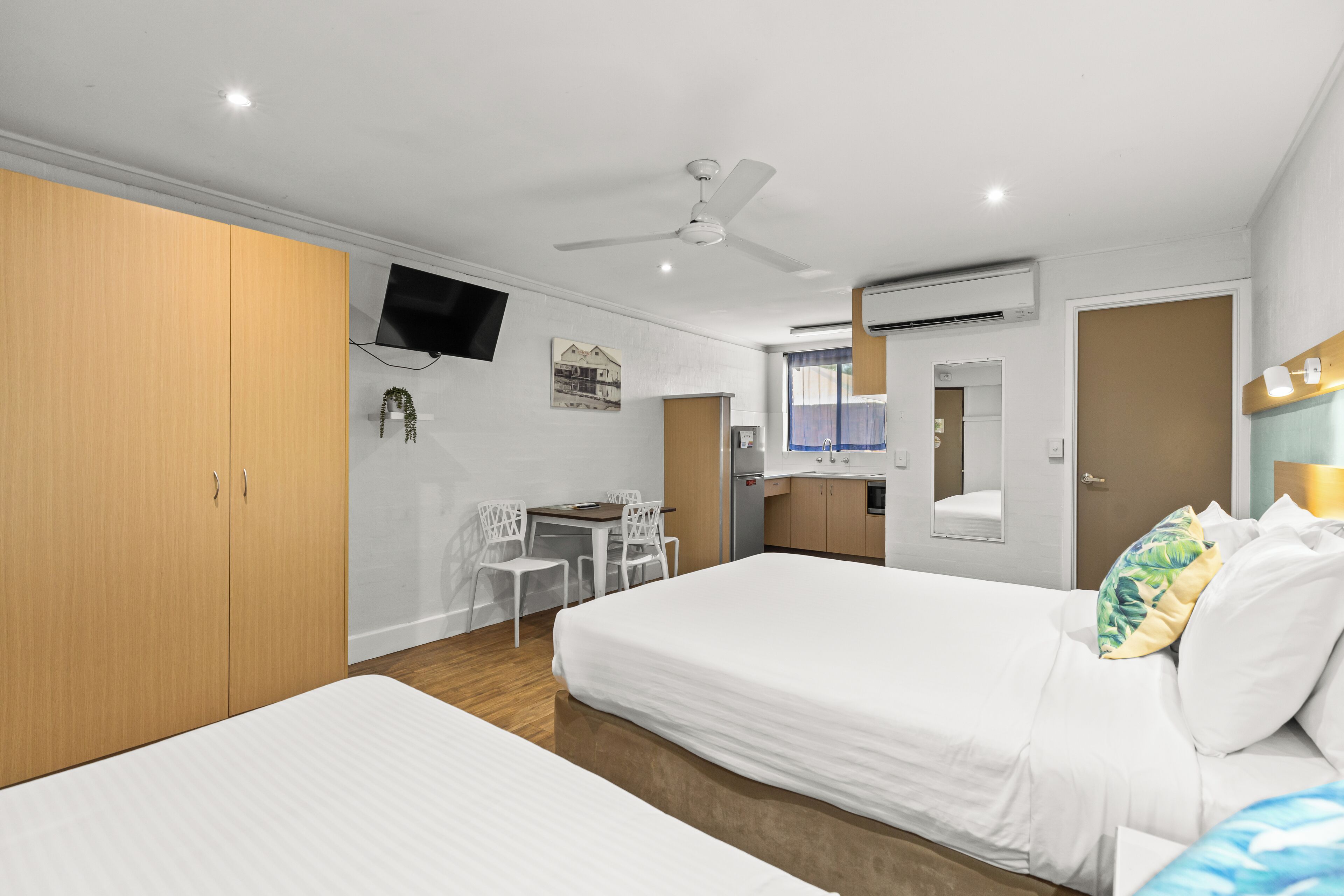 A hotel room with two beds, a desk, a chair, a TV, and a bathroom.