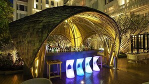 Un área de bar al aire libre con una estructura de techo de paja, barra y asientos.