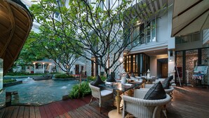 Una terraza de madera con mobiliario exterior, una piscina pequeña y un pabellón.