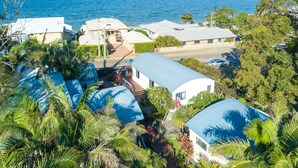Una zona residencial costera con casas, vistas despejadas al mar y abundante vegetación.