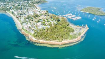 An aerial view of a coastal town with a marina, residential areas, and a forested island.