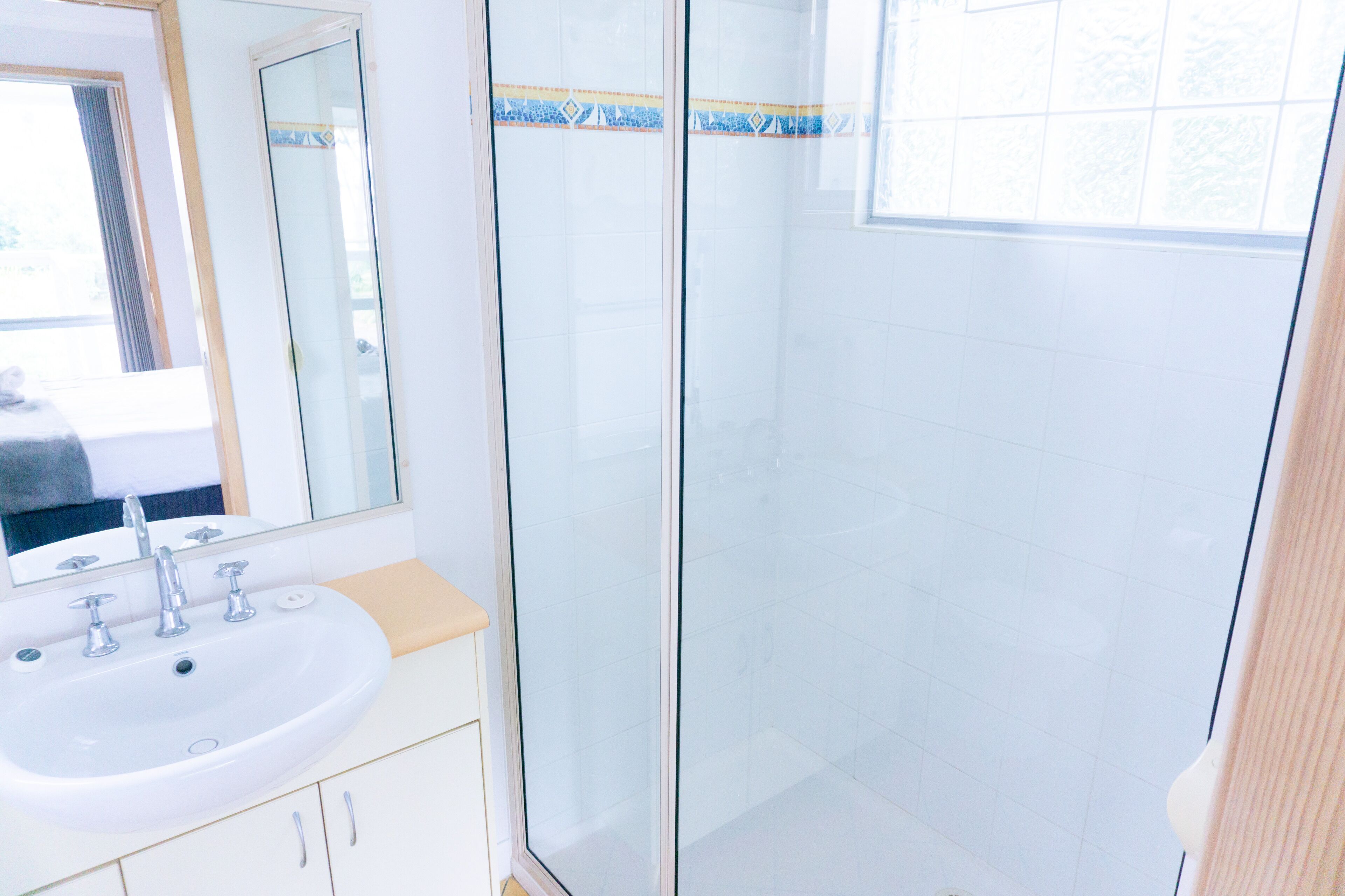 A bathroom with a white sink, a mirror, and a glass shower enclosure.
